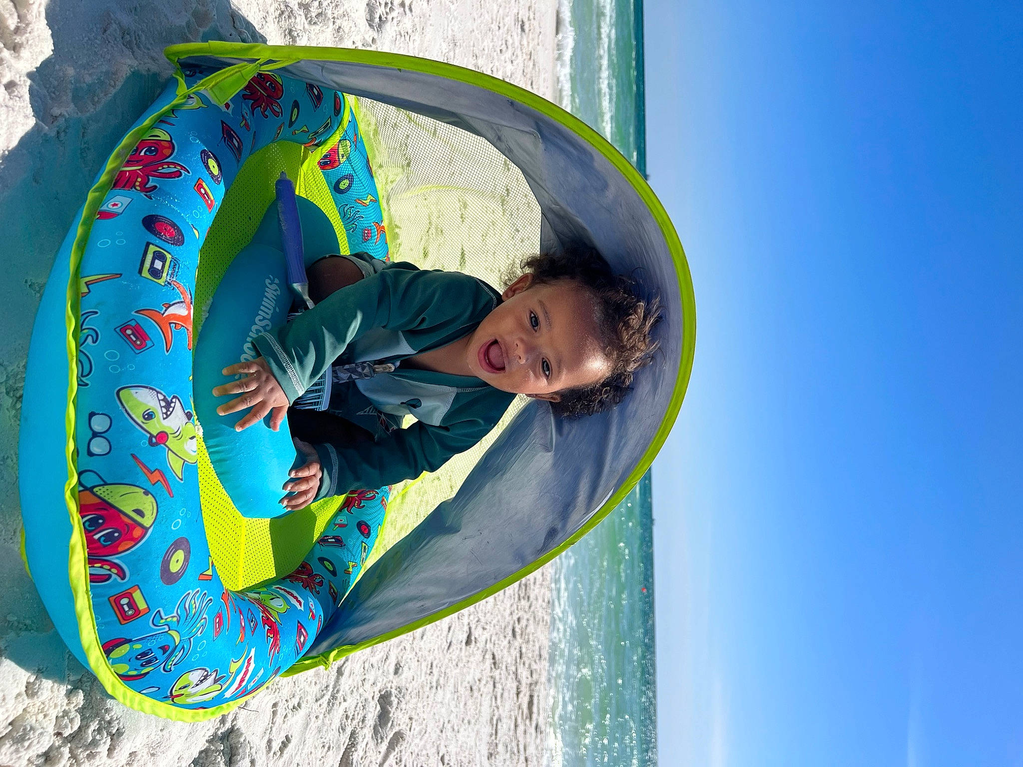 Zaiden is registered to the contest to win money with this photo: azure, blue, child, circle, electric_blue, eye, fun, happy, leisure, outdoor_play_equipment, pattern, people_in_nature, person, personal_protective_equipment, play, recreation, sky, smile, toddler, vacation