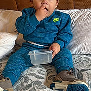 Bennett joined the competition — help win amazing prizes! child, toddler, boy, sitting, bed, blanket, pillow, headboard, nike_logo, tracksuit, blue_clothing, snack_container, hand, fingers, shoes, sneakers, hair, bangs, portrait, indoor