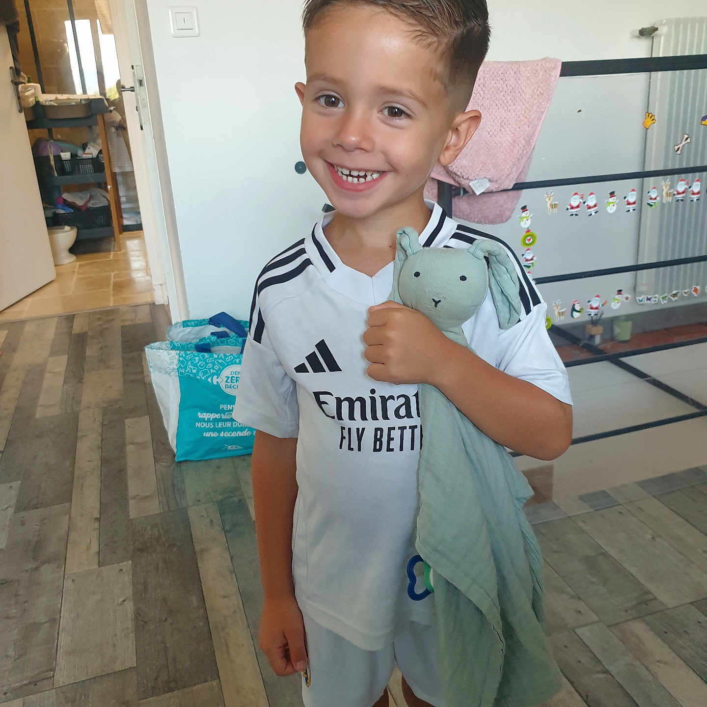 Tiago participe au concours pour gagner de l'argent avec cette photo : blanket, boy, casual, child, door, flooring, glass_panel, haircut, happy, home, indoor, person, radiator, shorts, smile, sock, sticker, stuffed_toy, toy, tshirt