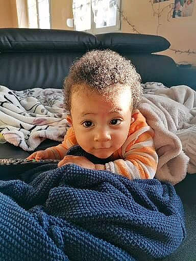 Kenzo participe au concours pour gagner de l'argent avec cette photo : baby, baby_toddler_clothing, cheek, child, comfort, couch, electric_blue, flooring, fur, happy, head, linens, nose, pattern, person, picture_frame, room, sitting, smile, toddler