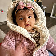 Zara is registered to the contest to win money with this photo: baby, child, pink_jacket, headband, bow, indoor, cozy, curious, knitted, hood, infant, person, portrait, cute, hand, face, expression, soft, warm, toy