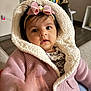 baby, child, pink_jacket, headband, bow, indoor, cozy, curious, knitted, hood, infant, person, portrait, cute, hand, face, expression, soft, warm, toy
