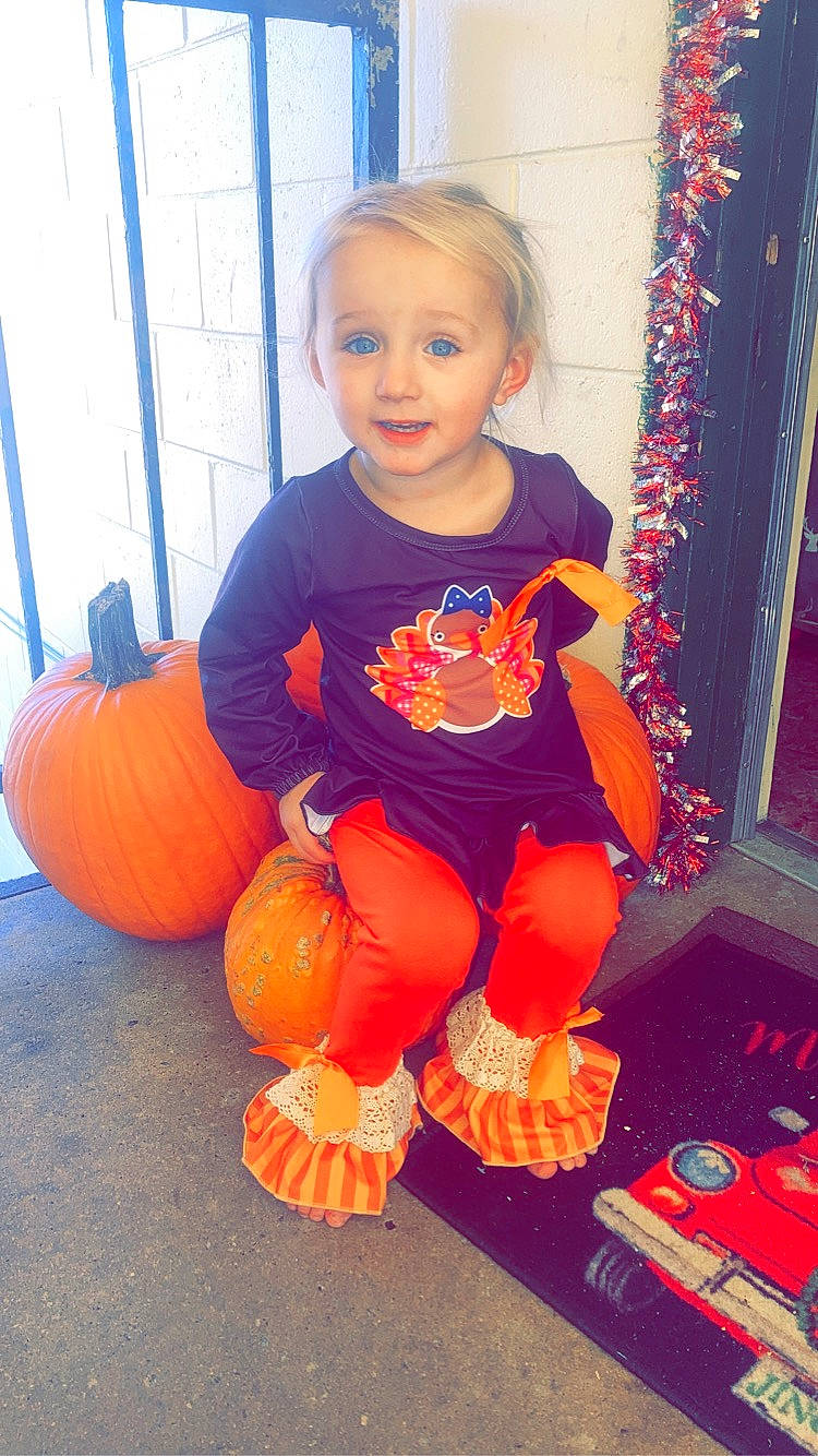 Blakelynn is registered to the contest to win money with this photo: baby_toddler_clothing, calabaza, child, cucurbita, door, flooring, gourd, hair, head, natural_foods, orange, person, plant, pumpkin, squash, standing, toddler, tree, vegetable, winter_squash