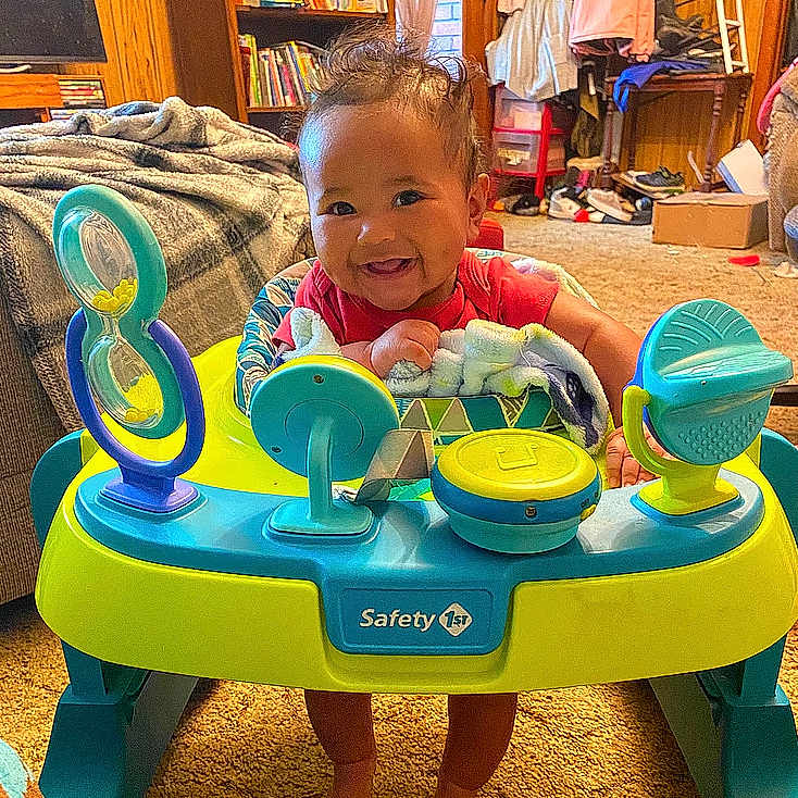 Naomi is registered to the contest to win money with this photo: baby, blackboard, box, clothing, couch, diningtable, face, footwear, furniture, happy, head, indoors, number, person, photography, portrait, shoe, sitting, symbol, text