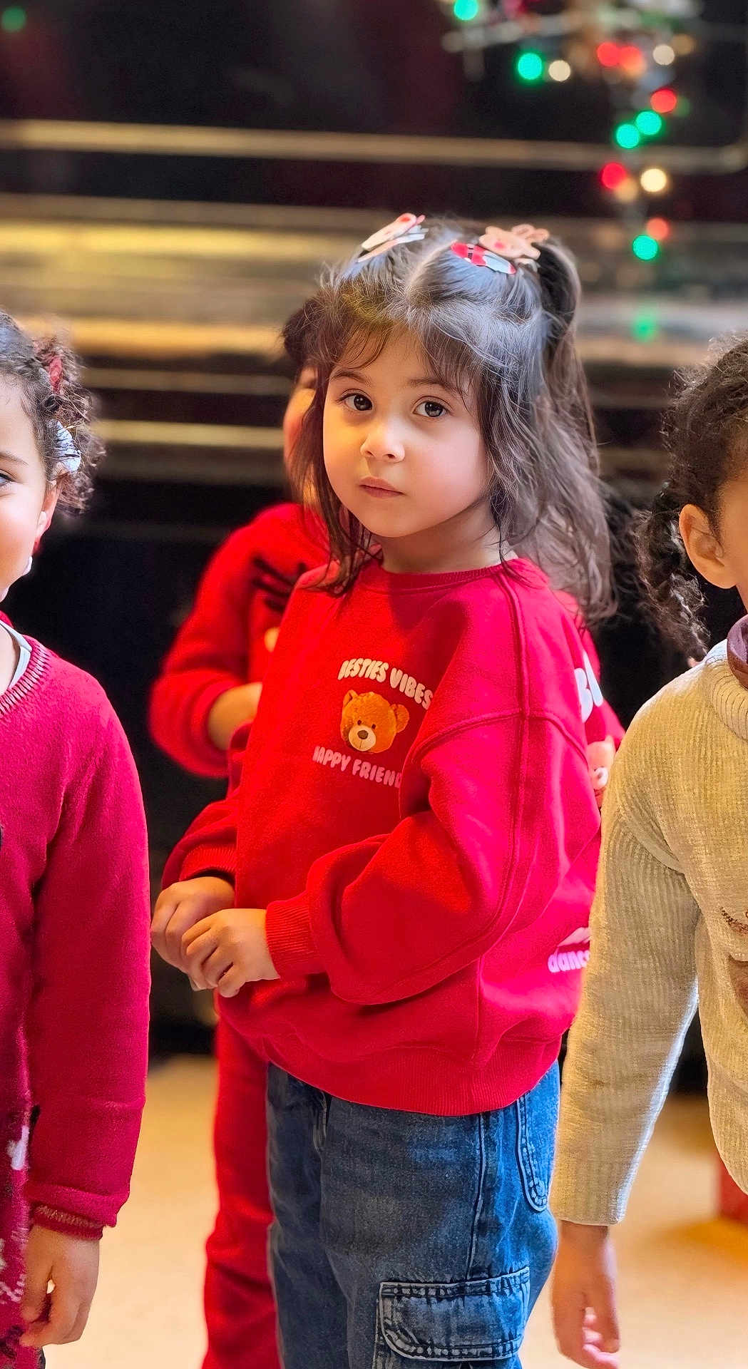 Tala a rejoint le concours — aidez-le/la à gagner de superbes lots ! child, children, red_sweatshirt, teddy_bear, hair_clips, jeans, indoor, friends, cute, portrait, young_girl, casual_clothing, long_hair, colorful_lights, festive, group, people, warm_lighting, soft_focus, expression