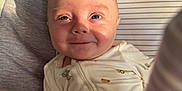 Kai is registered to the contest to win money with this photo: baby, infant, smile, face, blue_eyes, onesie, striped_cushion, soft_toys, sunlight, shadow, cozy, cute, child, closeup, indoor, fabric_tags, seat, playful, young, portrait