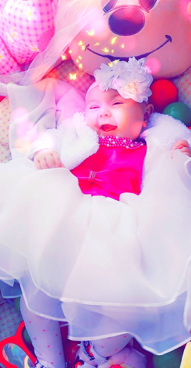 Djenna a rejoint le concours — aidez-le/la à gagner de superbes lots ! baby, baby_toddler_clothing, child, comfort, event, fun, happy, hat, headband, headwear, magenta, peach, person, petal, pink, purple, sitting, toddler, violet