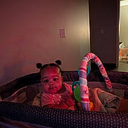 Miracle joined the competition — help win amazing prizes! baby, blanket, child, clothing, colorful, cozy, curious, doorway, floor, furniture, indoor, infant, person, pigtails, playpen, portrait, room, soft_lighting, toy, wall