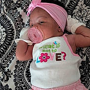 Miracle is registered to the contest to win money with this photo: baby, infant, pacifier, headband, mittens, pink_clothing, white_tank_top, patterned_blanket, lying_down, close_up, cute, sleepy, child, adorable, soft_lighting, portrait, resting, baby_girl, fabric, text_on_clothing