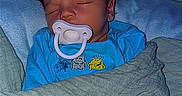 Mikah is registered to the contest to win money with this photo: baby, bed, blanket, blue_onesie, child, closed_eyes, cozy, cute, face, hair, indoors, infant, newborn, pacifier, resting, sleeping, soft_lighting, spiky_hair, toddler, wrapped