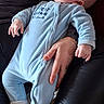 adult_hand, baby, blue_onesie, bracelet, child, closed_eyes, couch, cozy, hand, infant, lap, leather_couch, nap, onesie, pacifier, portrait, ring, sleeping, socks, soft_texture