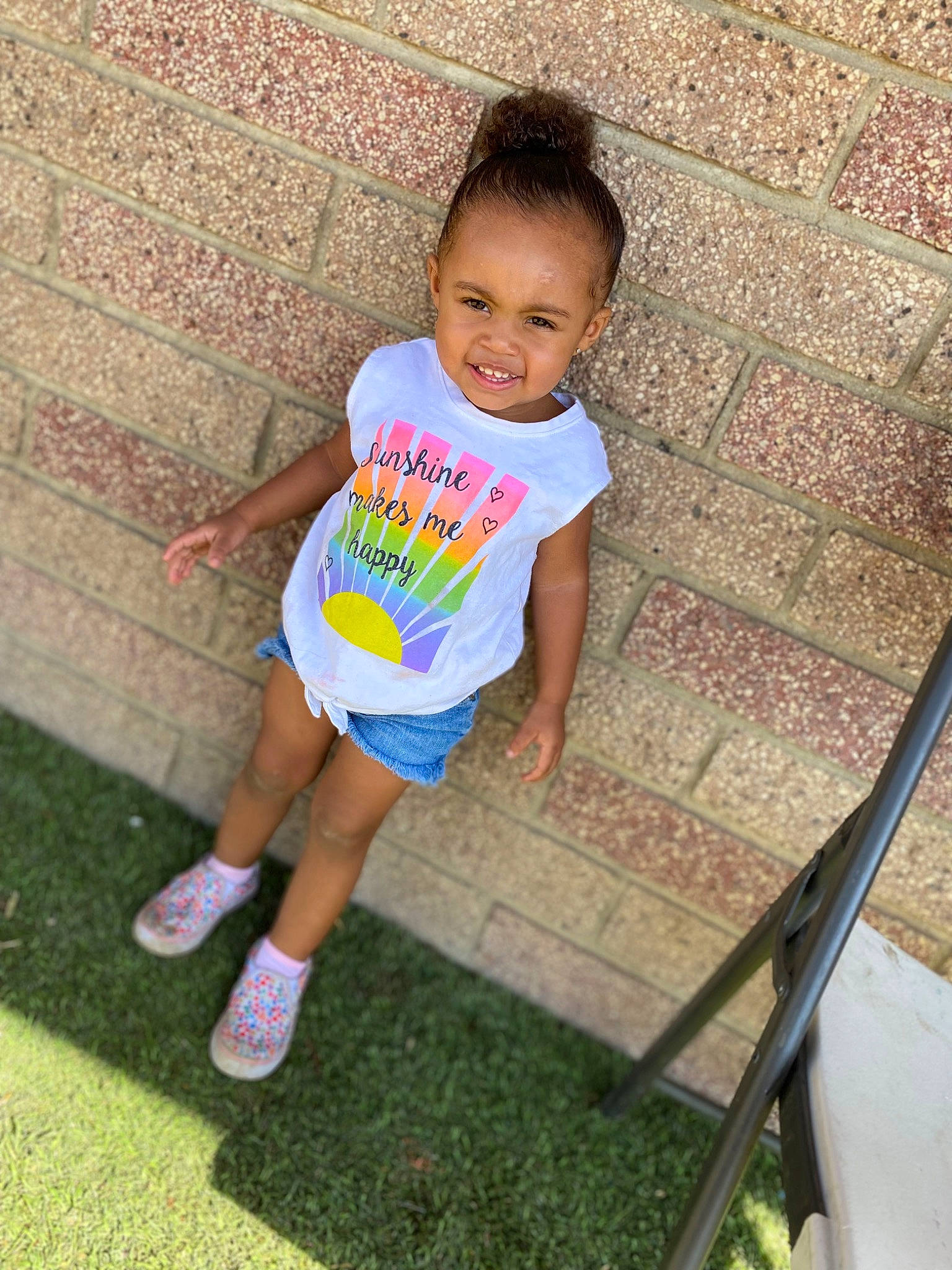 Amina is registered to the contest to win money with this photo: baby_toddler_clothing, chair, child, face, fun, grass, happy, human_leg, leg, leisure, magenta, person, plant, play, recreation, sandal, shorts, sitting, t_shirt, thigh