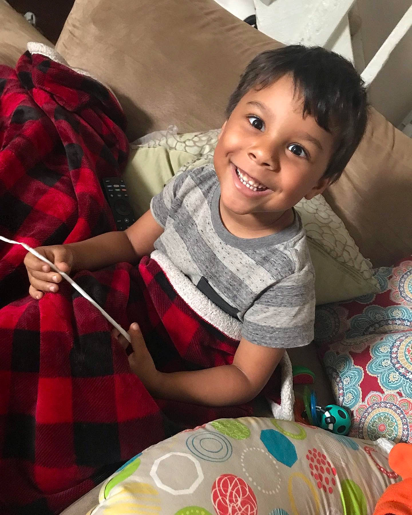 Keegan is registered to the contest to win money with this photo: chair, child, comfort, couch, finger, fun, happy, joy, leisure, linens, pattern, person, plaid, room, sitting, smile, t_shirt, table, tableware, tartan