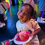 Kehlani is registered to the contest to win money with this photo: child, birthday_girl, cupcake, headband, pink_frosting, party, smile, colorful_background, candy, plate, tshirt, braided_hair, earrings, indoor, celebration, person, colorful_lighting, food, happy, minnie_mouse