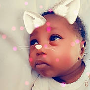 Skyler is registered to the contest to win money with this photo: baby, infant, face, ears, whiskers, nose, digital_filter, cat_ears, pink_bokeh, cute, child, lying_down, white_blanket, soft_lighting, portrait, closeup, expression, adorable, sleepwear, looking_up