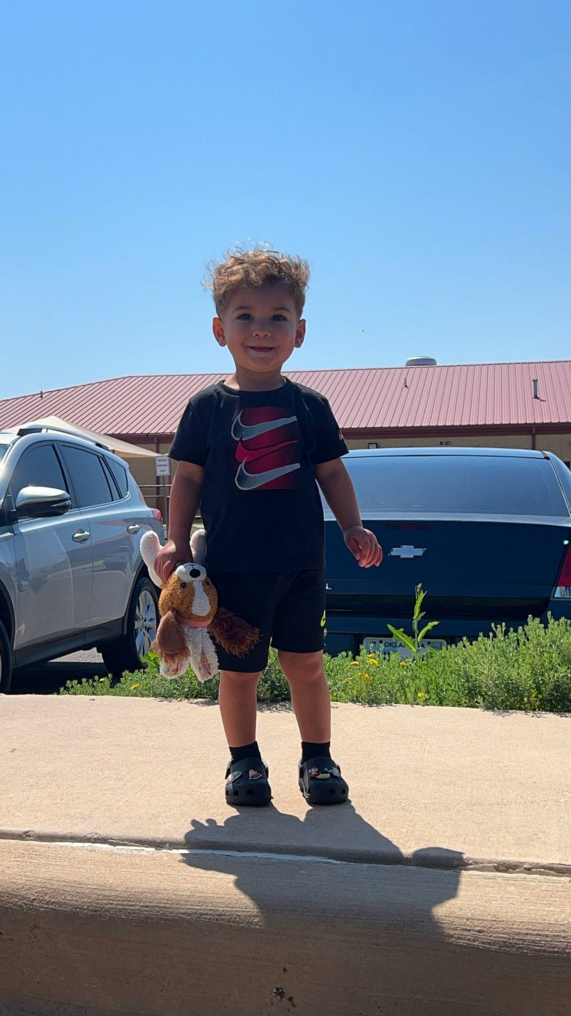 Mateo is registered to the contest to win money with this photo: asphalt, automotive_design, automotive_exterior, automotive_tire, bumper, car, joy, land_vehicle, leisure, motor_vehicle, person, plant, rolling, shorts, sky, tire, toddler, travel, vehicle, vehicle_door