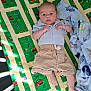 baby, bed, blanket, child, colorful, comfort, crib, cute, dinosaur_pattern, foot, indoors, infant, lying_down, patterned_fabric, quilt, shirt, shorts, soft_toys, sunlight, young_child