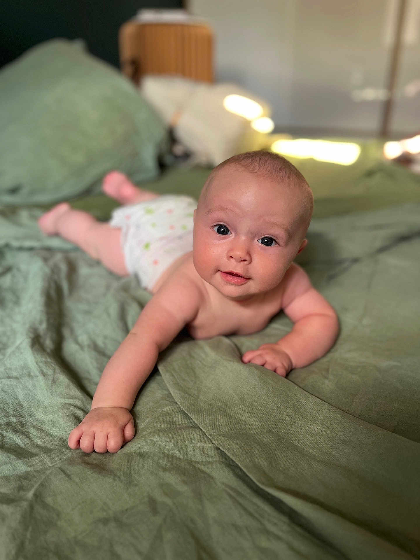 Jean participe au concours pour gagner de l'argent avec cette photo : arm, baby, bed, blanket, child, cute, diaper, eyes, face, furniture, hand, home, indoors, infant, lying_down, person, skin, smile, soft, young