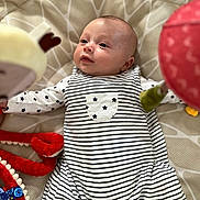 Jean a rejoint le concours — aidez-le/la à gagner de superbes lots ! baby, child, comfort, curious, cushion, cute, face, head, indoors, infant, long_sleeves, lying_down, pajamas, patterned_background, playtime, resting, soft_toys, stars, striped_clothing, young_child