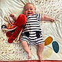 baby, bed, blanket, child, comfort, cute, feather_pattern, happy, indoor, infant, leaf_pattern, lying_down, octopus, pajamas, person, playful, plush_toy, smiling, soft_toy, striped_clothing