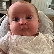Archie is registered to the contest to win money with this photo: baby, infant, face, eyes, clothing, white, indoors, expression, comfort, person, head, skin, cute, portrait, newborn, sitting, human, young, background, soft