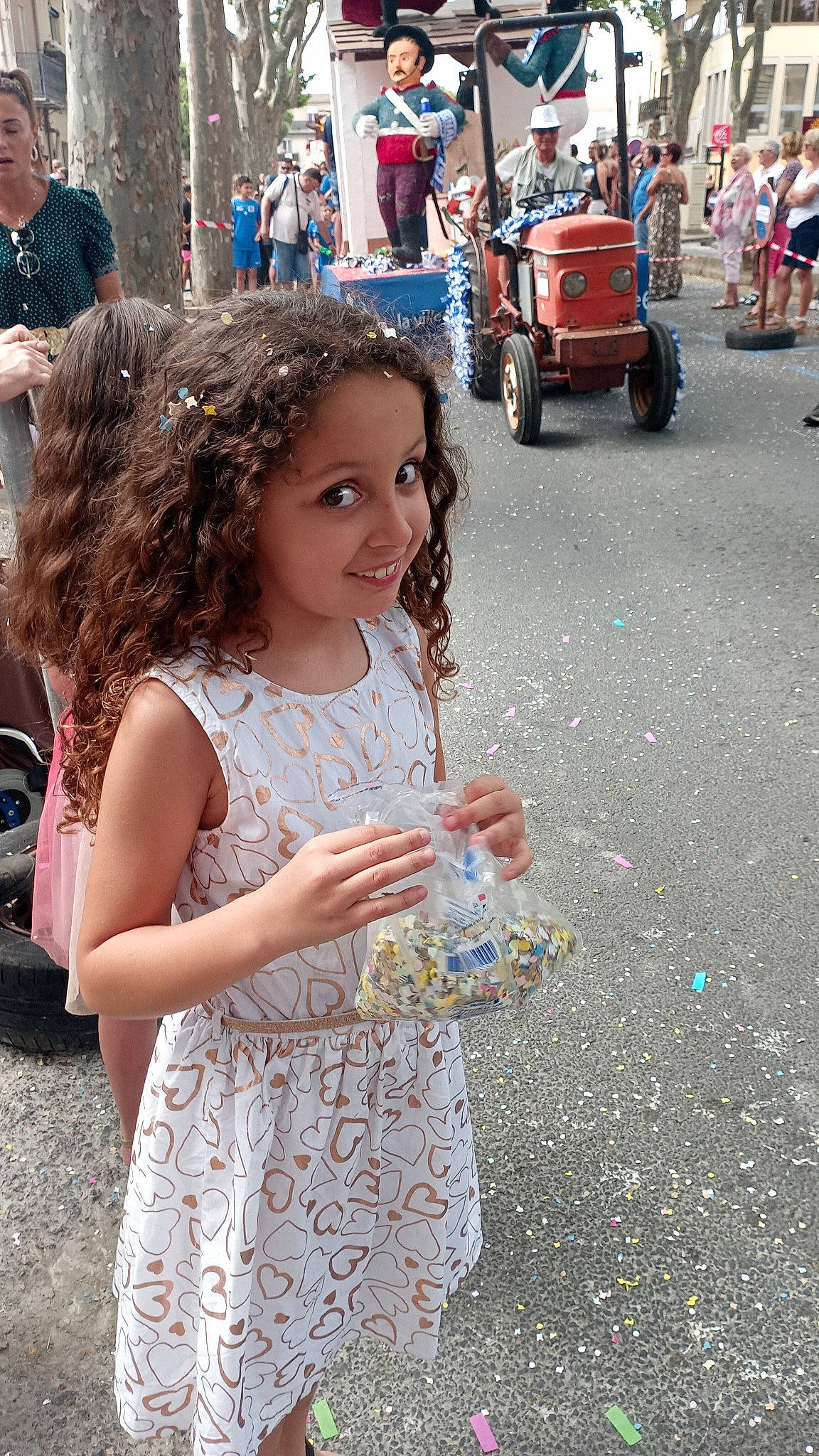 Naya a rejoint le concours — aidez-le/la à gagner de superbes lots ! asphalt, child, city, clothing, crowd, event, fun, happy, headwear, joy, leisure, motor_vehicle, person, pink, public_event, recreation, road, street, tire, toddler