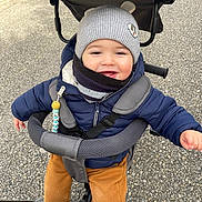 Julio participe au concours pour gagner de l'argent avec cette photo : accessory, baby, child, cold_weather, face, happy, hat, jacket, outdoor, pants, pavement, playful, scarf, seatbelt, shoes, smile, stroller, toddler, toy, winter_clothing