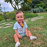Julio a rejoint le concours — aidez-le/la à gagner de superbes lots ! toddler, child, grass, outdoor, garden, greenery, tree, smile, sitting, bib, tshirt, playful, nature, path, plant, countryside, daytime, cute, young, happy