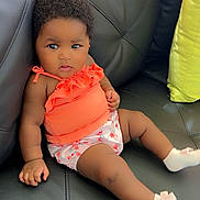 Armony Cara Francis is registered to the contest to win money with this photo: baby, infant, child, couch, black_leather, orange_top, floral_shorts, socks, pink_bows, indoor, furniture, cute, portrait, relaxed, seated, curious, skin, hair, small_hands, expression
