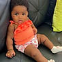 baby, infant, child, couch, black_leather, orange_top, floral_shorts, socks, pink_bows, indoor, furniture, cute, portrait, relaxed, seated, curious, skin, hair, small_hands, expression