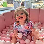 Ellie joined the competition — help win amazing prizes! baby, ball_pit, child, cozy, cute, floral_dress, furniture, garden, glass_door, happy, indoor, pink_balls, play, portrait, seated, smiling, socks, toys, white_balls, window