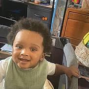 Kevin joined the competition — help win amazing prizes! basket, child, clutter, curious, desk, floor, furniture, green_bib, home, indoor, lamp, person, playpen, printer, smiling, standing, toddler, toy, white_shirt, wooden_drawer