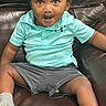 Kevin is registered to the contest to win money with this photo: toddler, child, sitting, leather_chair, turquoise_shirt, gray_shorts, socks, indoor, curly_hair, playful_expression, wide_eyes, person, casual_clothing, comfortable, young_child, portrait, furniture, relaxed, skin_tone, seated