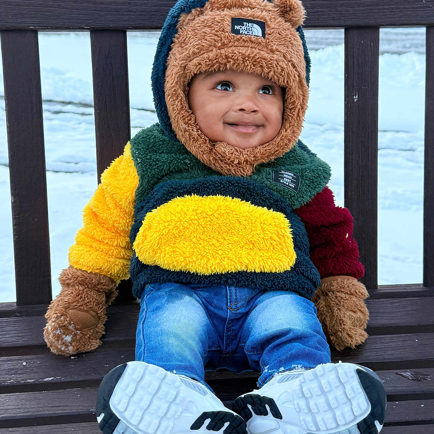 Kevin is registered to the contest to win money with this photo: toddler, child, bench, winter, snow, coat, hood, gloves, jeans, sneakers, smile, outdoor, cold_weather, cute, fashion, playful, face, park, seasonal, happy