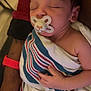 baby, sleeping, pacifier, blanket, striped_blanket, arm, person, hand, resting, cute, infant, child, sleep, comfort, soft, closeup, indoors, peaceful, newborn, wrapped