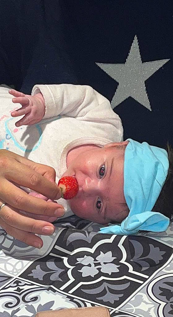 Letna participe au concours pour gagner de l'argent avec cette photo : baby, baby_safety, baby_toddler_clothing, child, finger, food, fruit, gesture, hand, headwear, human_body, lip, mouth, nail, natural_foods, person, product, skin, strawberry, textile