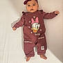 baby, infant, clothing, headband, maroon, daisy_duck, cartoon, lying_down, cute, face, wide_eyes, small_hands, small_feet, onesie, portrait, child, soft_light, indoor, person, baby_girl