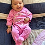 baby, infant, smiling, pink_onesie, bedspread, lying_down, child, cute, happy, indoors, soft_texture, patterned_bedspread, person, portrait, young_child, cozy, sleepwear, small_hand, cheerful, head