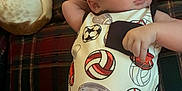 Sawyer joined the competition — help win amazing prizes! baby, infant, dog, couch, plaid, onesie, sports, football, volleyball, baseball, hand, tattoo, pet, relaxing, indoor, face, person, furniture, animal, resting