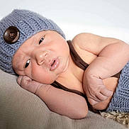 Sawyer joined the competition — help win amazing prizes! baby, infant, knitted_hat, knitted_clothing, button, lying_down, beige_background, soft_texture, cute, newborn, face, arm, hand, sleepy, portrait, skin, indoors, closeup, warm, resting