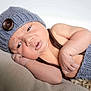 baby, infant, knitted_hat, knitted_clothing, button, lying_down, beige_background, soft_texture, cute, newborn, face, arm, hand, sleepy, portrait, skin, indoors, closeup, warm, resting