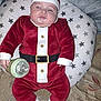 Ethan is registered to the contest to win money with this photo: baby, infant, santa_claus_costume, red_clothing, white_trim, bottle, milk, pillow, star_pattern, sleepy, lying_down, sock, cute, holiday, festive, indoor, child, face, hand, soft_fabric
