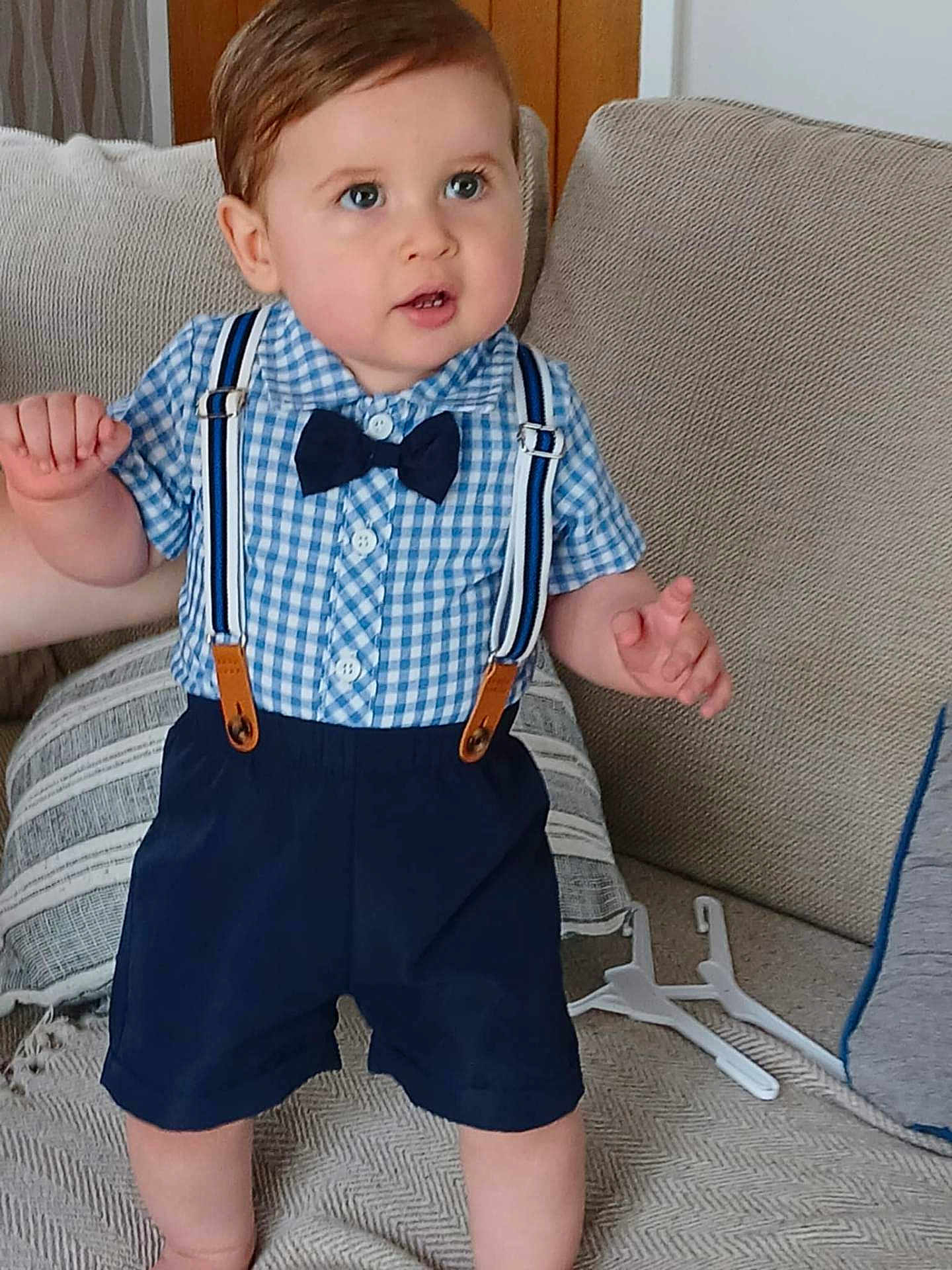 Ethan joined the competition — help win amazing prizes! toddler, child, boy, clothing, bow_tie, suspenders, blue_shirt, shorts, couch, cushions, indoor, person, standing, home, furniture, cute, face, hair, skin, expression