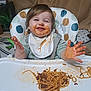 baby, bib, child, clothing, expression, face, food, fun, hair, hands, happy, high_chair, indoor, meal, messy, plate, smiling, spaghetti, table, toddler