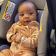 Rayven joined the competition — help win amazing prizes! baby, child, car_seat, onesie, unicorn, flower_pattern, clothing, infant, cute, portrait, seatbelt, straps, indoor, person, expression, hands, head, face, eyes, smile