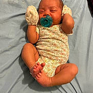 Rayven joined the competition — help win amazing prizes! baby, newborn, pacifier, mittens, onesie, infant, sleeping, bed, blue_sheet, skin, foot, hand, clothing, person, cute, peaceful, lying_down, indoors, floral_pattern, small