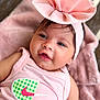 baby, child, headband, pink, smile, face, infant, clothing, blanket, cute, portrait, soft_texture, happy, young_child, indoors, closeup, person, apparel, resting, fashion