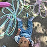toddler, child, chalk, sidewalk, drawing, flower, colorful, chalk_sticks, jeans, white_shirt, sneaker, outdoor, play, art, concrete, curly_hair, hand, expression, shoes, sunlight