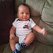Antonio Jr. is registered to the contest to win money with this photo: arms, baby, bodysuit, casual, child, clothing, couch, face, furniture, happy, indoors, infant, legs, nike, patterned_fabric, portrait, sitting, smiling, socks, sofa