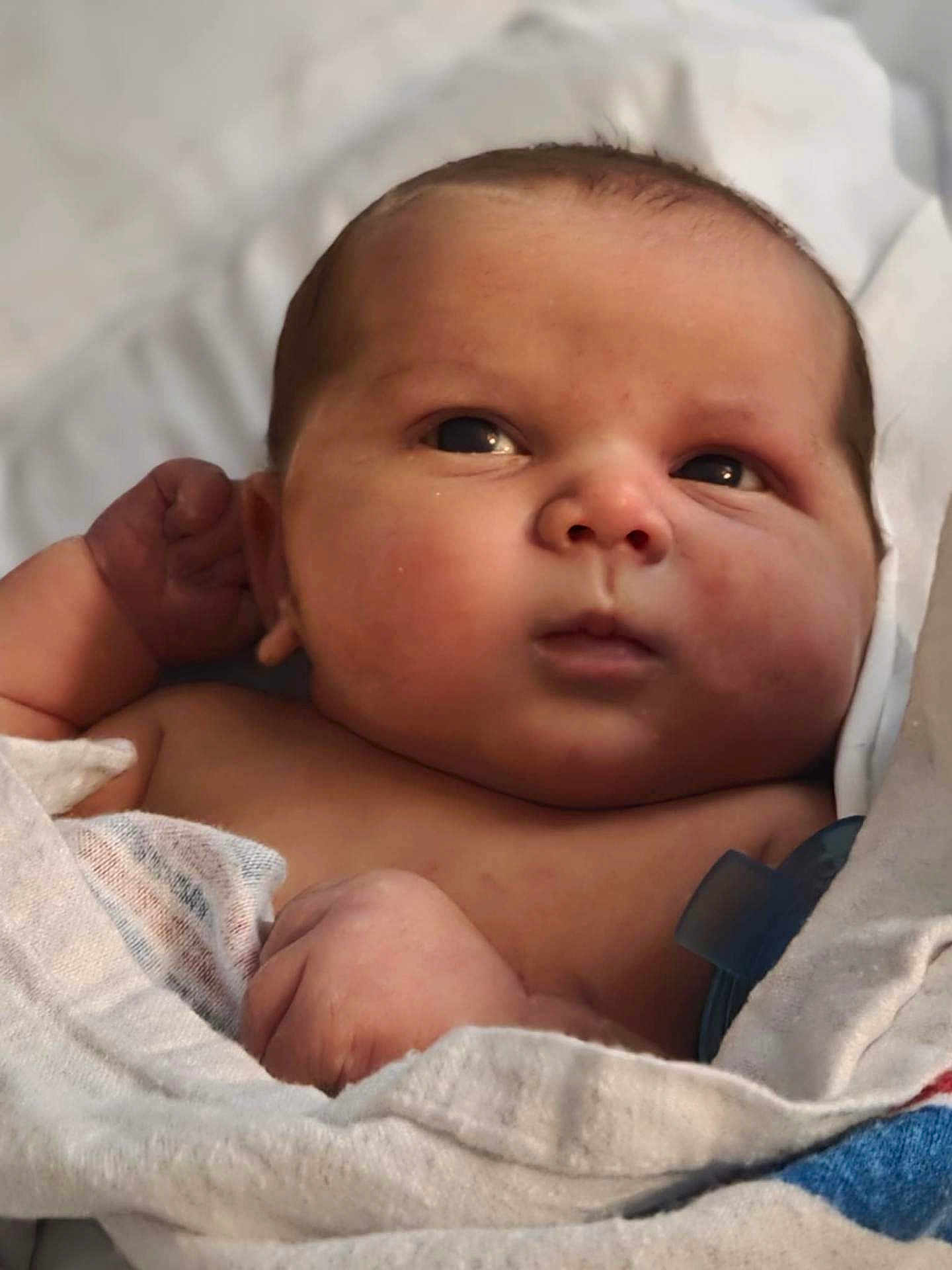 Carter is registered to the contest to win money with this photo: baby, infant, face, skin, blanket, wrapped, newborn, cute, expression, hands, closeup, portrait, child, soft, indoors, resting, curious, young, human, person